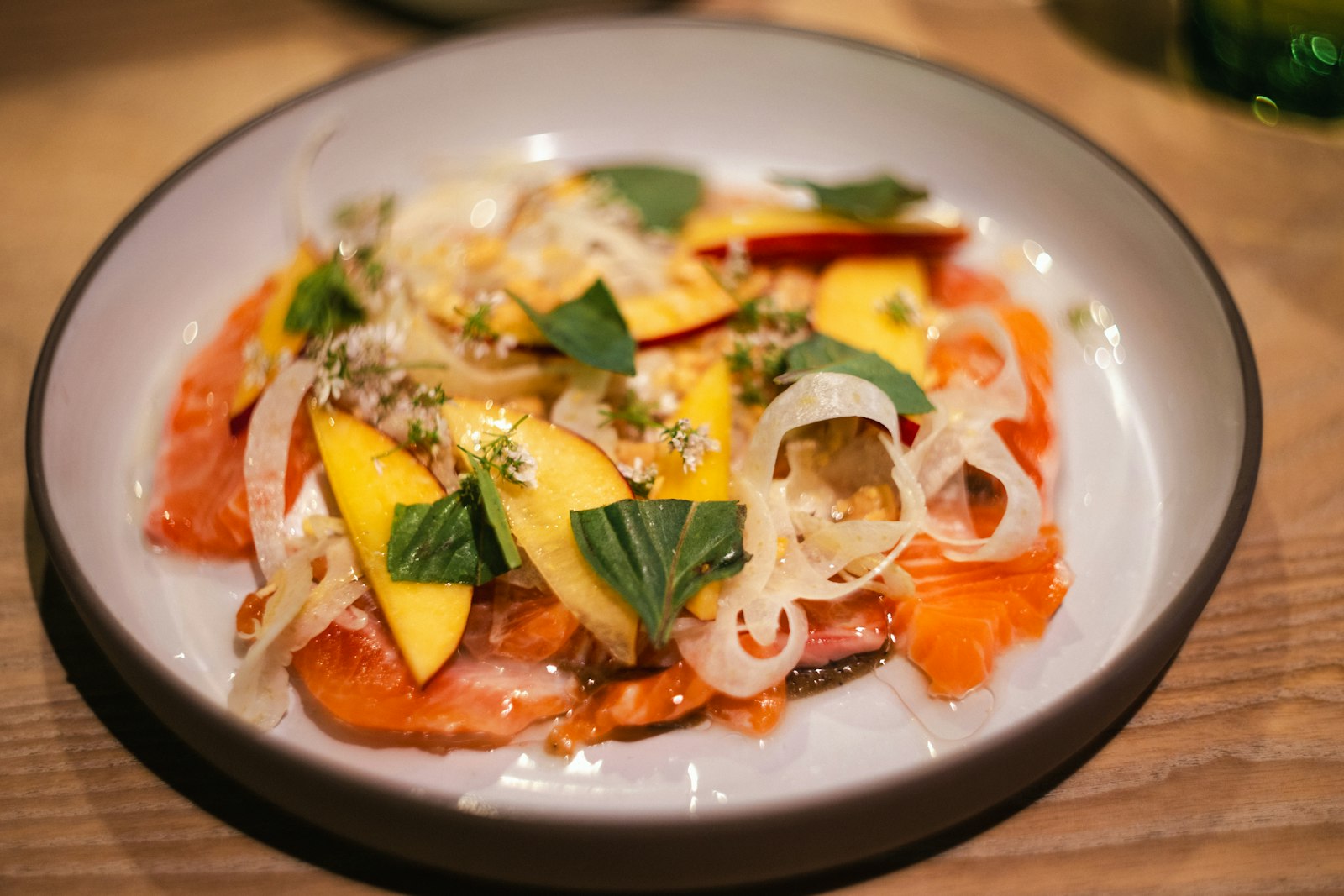 Salmon carpaccio plated with mango and herbs