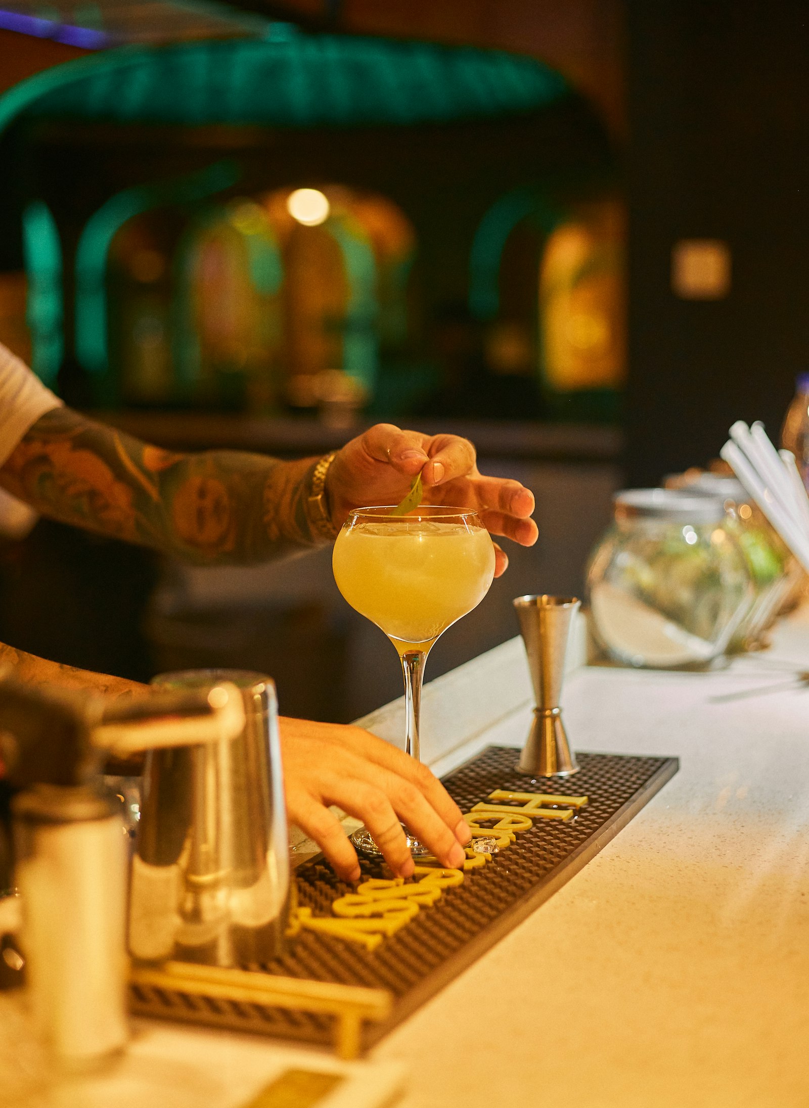 Bartender garnishing a cocktail with a lime wedge