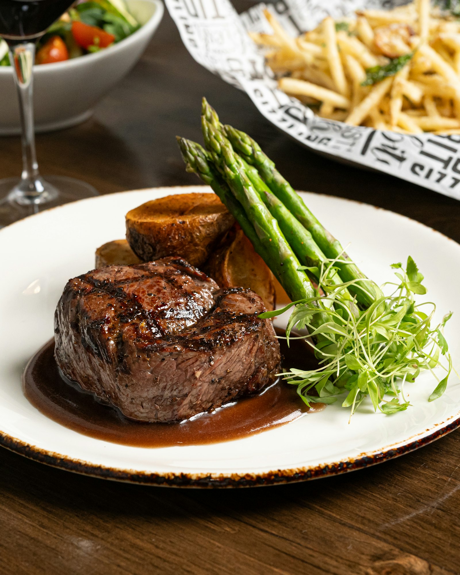 Sliced steak plated with asparagus and a glass of wine