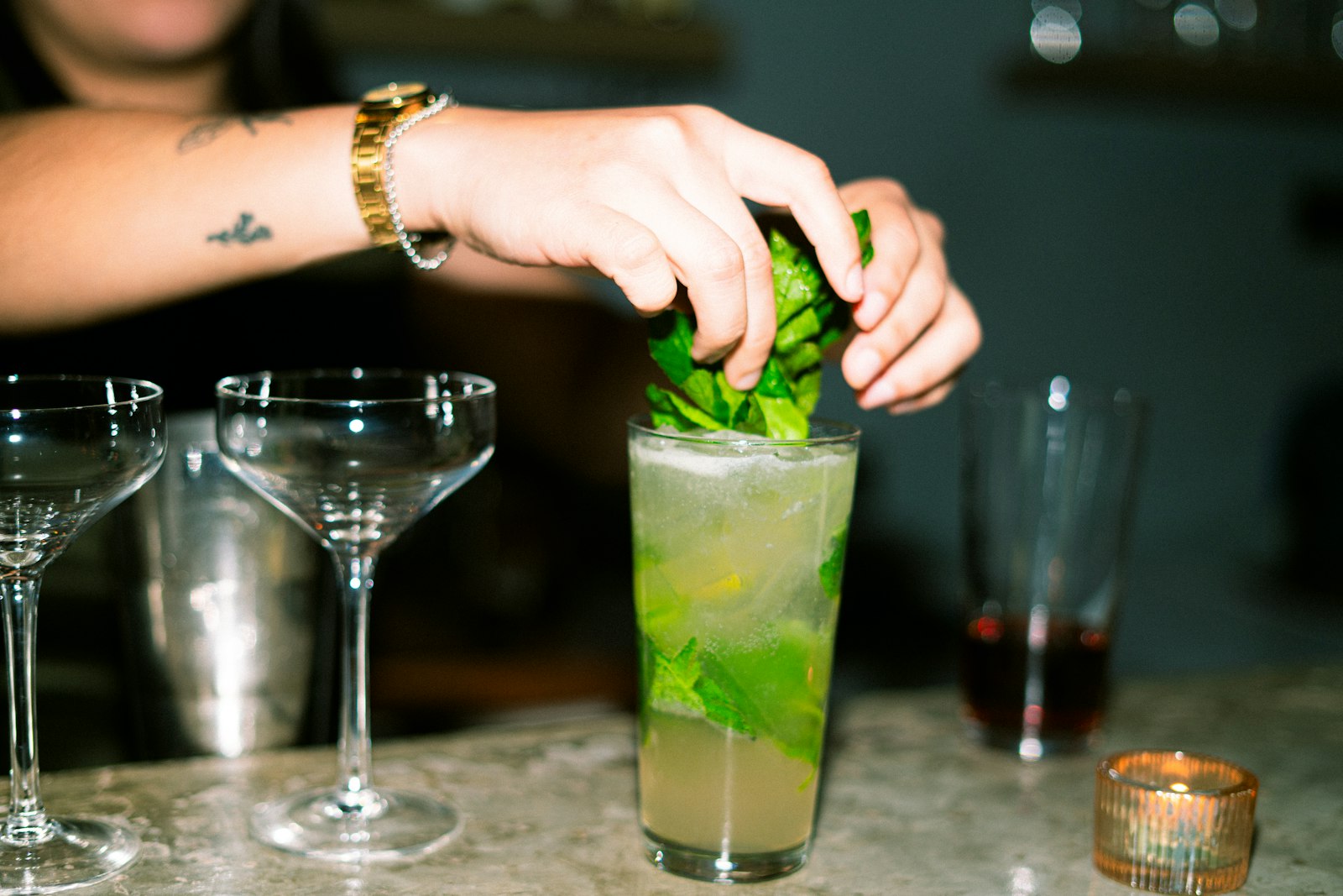 Bartender garnishing a cocktail with fresh mint